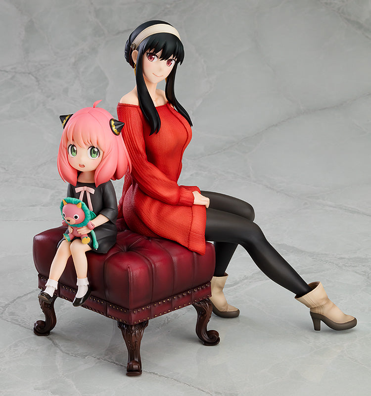 Official GSC SPY x FAMILY Anya & Yor 1/7 scale figure close-up, Yor in red knit dress with Anya on lap holding Chimera plushie, casual pose on red ottoman